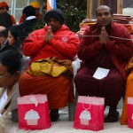 Buddhist monks seated in an outdoor ceremony.